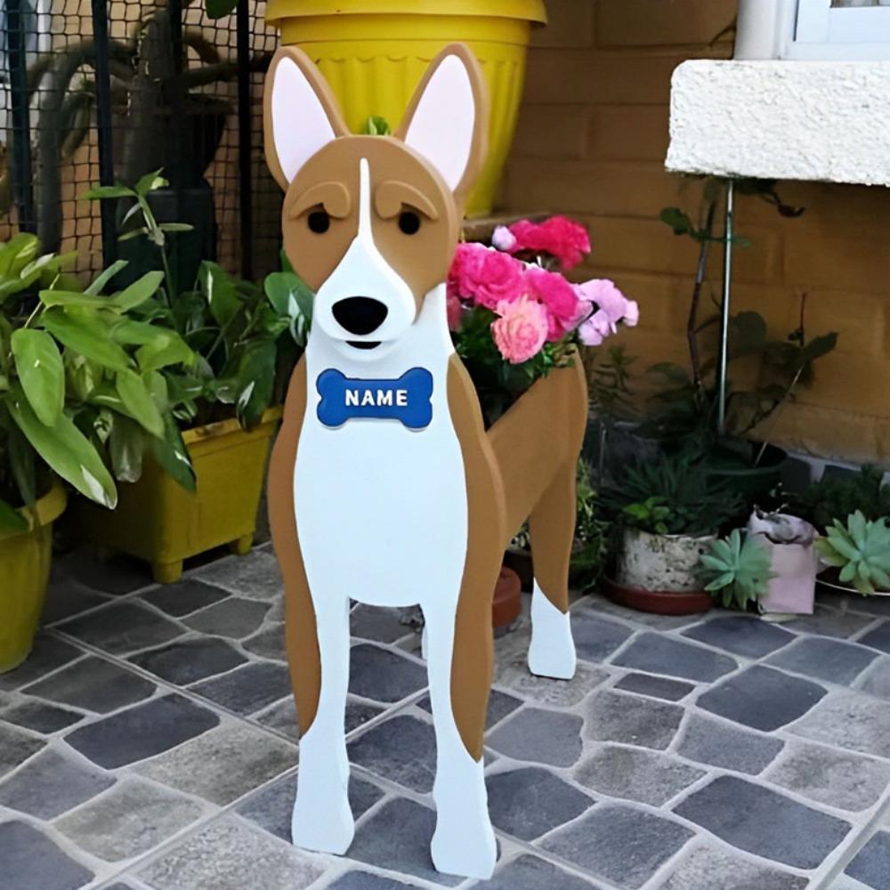 Basenji-shaped dog planter with a blue name tag on a stone patio surrounded by potted plants
