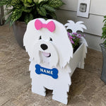 Coton de Tulear dog planter filled with fresh flowers is placed in the garden
