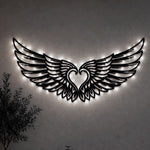 Black metal Cupid Heart wings wall art with Soft White LED Lighting displayed on the wall