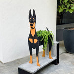 Doberman dog planter filled with fresh flowers is placed in the garden