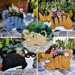 Lying cats planter filled with fresh flowers is placed in the garden
