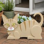 Lying cats planter filled with fresh flowers is placed in the garden