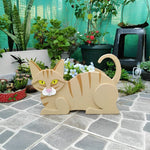 Lying cats planter filled with fresh flowers is placed in the garden