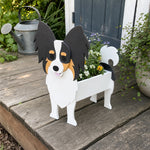 Papillon dog planter filled with fresh flowers is placed in the garden